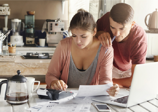 Young caucasian couple reviewing finances, with woman holding piece paper calculating finances