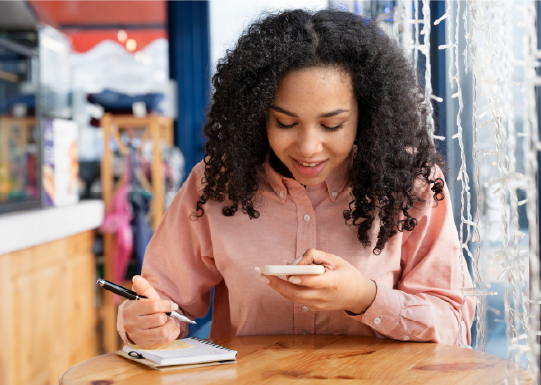 Smiley woman reading from phone and taking notes