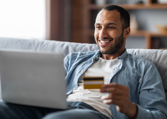 Cheerful man using laptop credit card